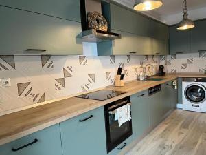 a kitchen with green cabinets and a washer and dryer at City Vibe Apartments in Someşeni