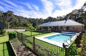 a house with a fence around a swimming pool at Husky Hideaway in Woollamia