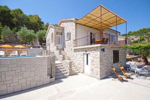 a stone villa with a swimming pool and a patio at House Tonko in Postira