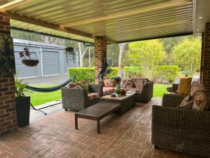 a patio with couches and chairs under a pergola at Husky Hideaway in Woollamia
