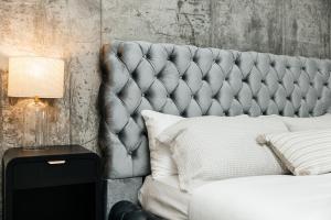 a bed with a tufted headboard next to a side table at Hollywood Designer Apartment in Los Angeles