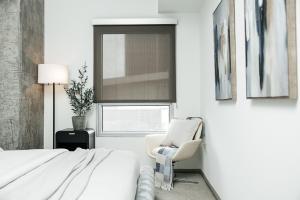 a bedroom with a bed and a chair and a window at Hollywood Designer Apartment in Los Angeles