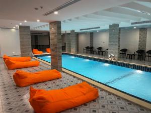 a large swimming pool with orange pillows around it at فندق فربيون المجاردة - Ferbion Hotel Almajardah in Al Majaridah