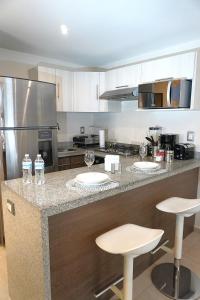a kitchen with a counter with three bar stools at Magnífico departamento, muy bien ubicado. in Mexico City