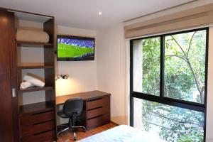 a bedroom with a desk and a tv and a window at Magnífico departamento, muy bien ubicado. in Mexico City +9 photos