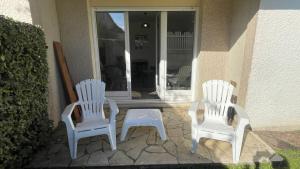 2 weiße Stühle und ein Tisch auf einer Veranda in der Unterkunft Studio avec jardin centre ville Cabourg La Roseraie in Cabourg