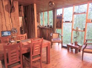 a dining room with a table and chairs and windows at Casa Bosque Villarrica in Voipire