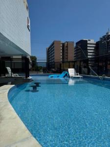 a large swimming pool with chairs in a building at Lindo APTO na Ponta Verde in Maceió