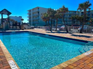 a large blue swimming pool with palm trees and a building at Superior beach studio with Pool Access and free parking in Daytona Beach