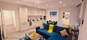 a living room with a blue couch and a kitchen at Abbey Corner By Nivaas 4-Located in the heart of the city centre-5 minute walk to train station-20 minutes to London via train in Reading