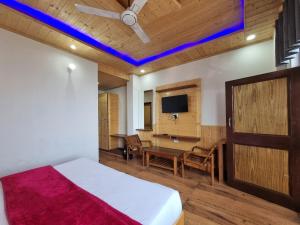 a bedroom with a bed and a desk and a tv at Grand Kailash view homestay -near Khajjiar in Dalhousie +63 photos