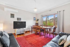 a living room with a table and a tv at Cascade Cottage adjoining World Heritage Site in Hobart