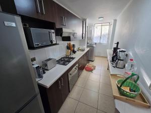 a kitchen with a refrigerator and a stove top oven at Hermoso Departamento Equipado por Días in Arica