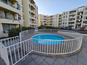 a swimming pool with a white rail next to a building at Hermoso Departamento Equipado por Días in Arica