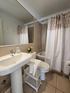 a white bathroom with a sink and a toilet at Hermoso Departamento Equipado por Días in Arica