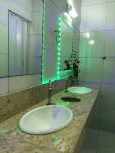 a bathroom with two sinks and a mirror with green lights at Casa na Praia de Iracema R&S in Fortaleza