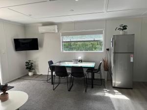 a room with a table and chairs and a refrigerator at The Hidden Cottage in Papamoa