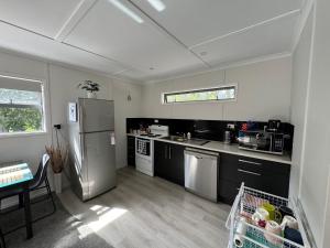 a kitchen with a stainless steel refrigerator and a table at The Hidden Cottage in Papamoa +3 photos