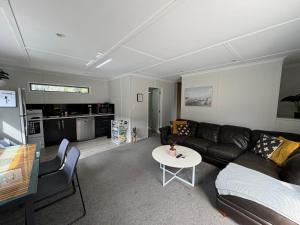 a living room with a couch and a table at The Hidden Cottage in Papamoa