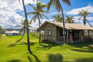 a small house with palm trees in front of a yard at Apartamento 03 suítes - Tree Bies Beach Resort - Praia de Subaúma in Entre Rios