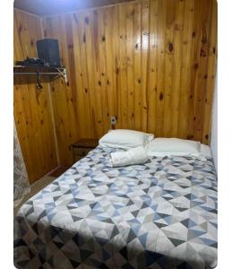 a bed in a room with a wooden wall at Casa de madeira 262 in Campos do Jordão