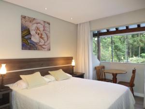 Un dormitorio con una gran cama blanca y una ventana en Residencial Jardim dos Pinheiros 279, en Canela