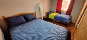 ein Schlafzimmer mit einem Bett mit einer blauen Bettdecke in der Unterkunft Casa interior cercana aeropuerto in Santiago