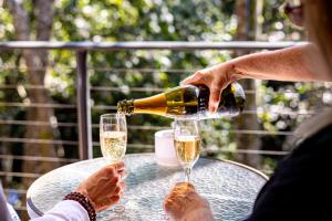 a woman pouring champagne into two glasses on a table at Tranquil Getaways On Obi Maleny in Maleny