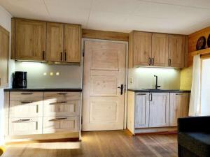 an empty kitchen with wooden cabinets and a door at Thorau Alm Comfortable in Ruhpolding
