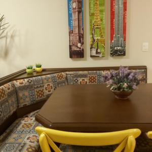 a dining room table with a yellow chair around it at Apartamento aconchego in Gramado
