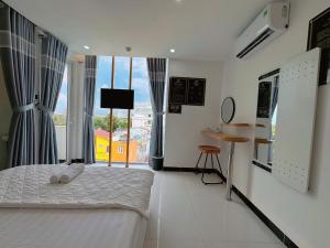 a bedroom with a bed and a table and window at Cen Hotel in Vung Tau