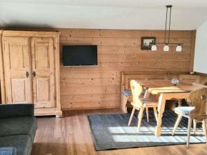 a living room with a wooden table and a tv at Thorau Alm Comfortable in Ruhpolding +17 photos