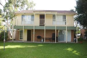 a large house with a balcony and a yard at Paws and Pause at The Bay in Callala Bay