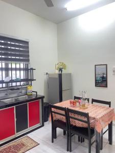 a kitchen with a table and chairs and a kitchen with a sink at Homestay Sri Aliff in Sri Gading