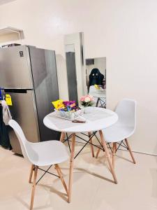 a white table with two chairs and a refrigerator at Asahel Cozy Crib Budget studio with Netflix in Buri