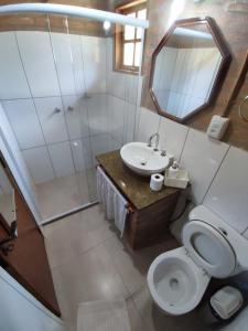 ein Badezimmer mit Toilette, Waschbecken und Spiegel in der Unterkunft Casa do Bosque in Visconde De Maua