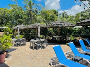 a patio with blue chairs and tables and umbrellas at Bijoutier Apartments in Grand'Anse Praslin