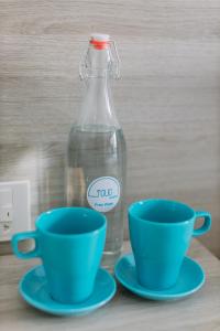 two blue cups and a glass bottle on a table at Tò Vò Hostel Nguyễn Công Trứ in Hue