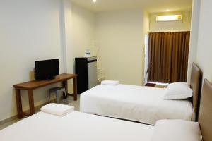 een kamer met 2 bedden, een bureau en een televisie bij J-House Phetchaburi in Phetchaburi