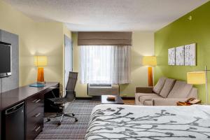 a hotel room with a bed and a desk and a couch at Sleep Inn & Suites Harbour Pointe in Brandermill
