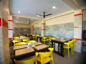 a restaurant with wooden tables and yellow chairs at Blue Stone Hotel & Restaurant Mandarmani in Mandarmoni