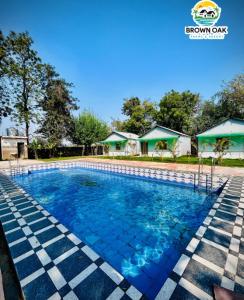 a swimming pool at a resort with blue water at Brown Oak Farms in Sohna