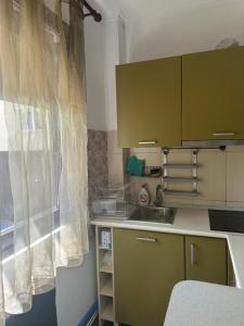 a kitchen with green cabinets and a sink and a window at Căsuța din povești in Oradea