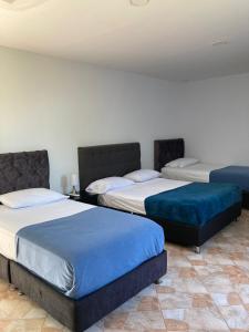 a room with two beds with blue cushions at Thiago Hotel campestre in Armenia +37 photos