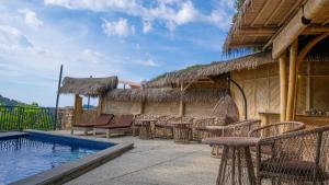 a resort with a swimming pool and tables and chairs at Elang Hillside Bamboo Villas in Labuan Bajo