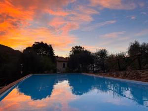 a large swimming pool with a sunset in the background at Ai Cinque Campanili in Finale Ligure
