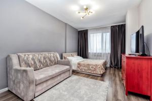 un soggiorno con un divano e una televisione di Уютные апартаменты в Астане a Astana