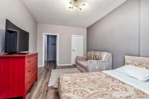 una camera con letto, TV e sedia di Уютные апартаменты в Астане a Astana