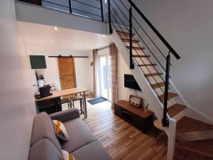 a living room with a couch and a staircase at Au Petit Nid in Bergues