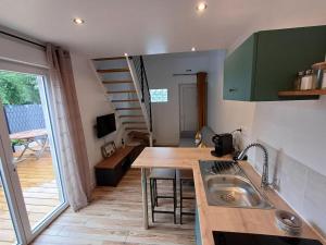 a kitchen with a sink and a table and a staircase at Au Petit Nid in Bergues